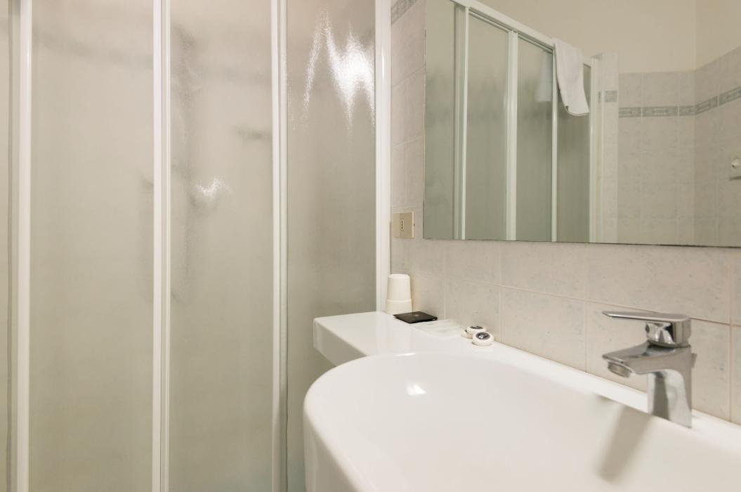 Bagno moderno, doccia con vetro opaco, lavabo elegante, atmosfera pulita e minimalista.