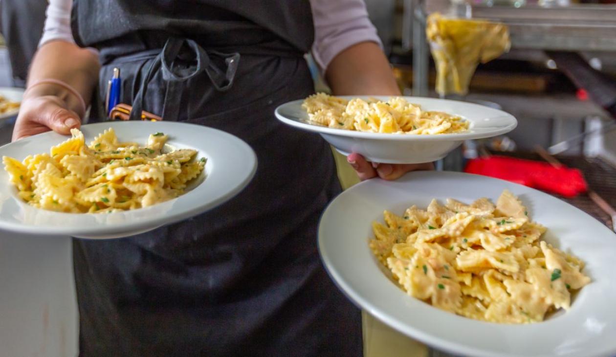 Un cameriere serve tre piatti di pasta farfalle, deliziosa e invitante.