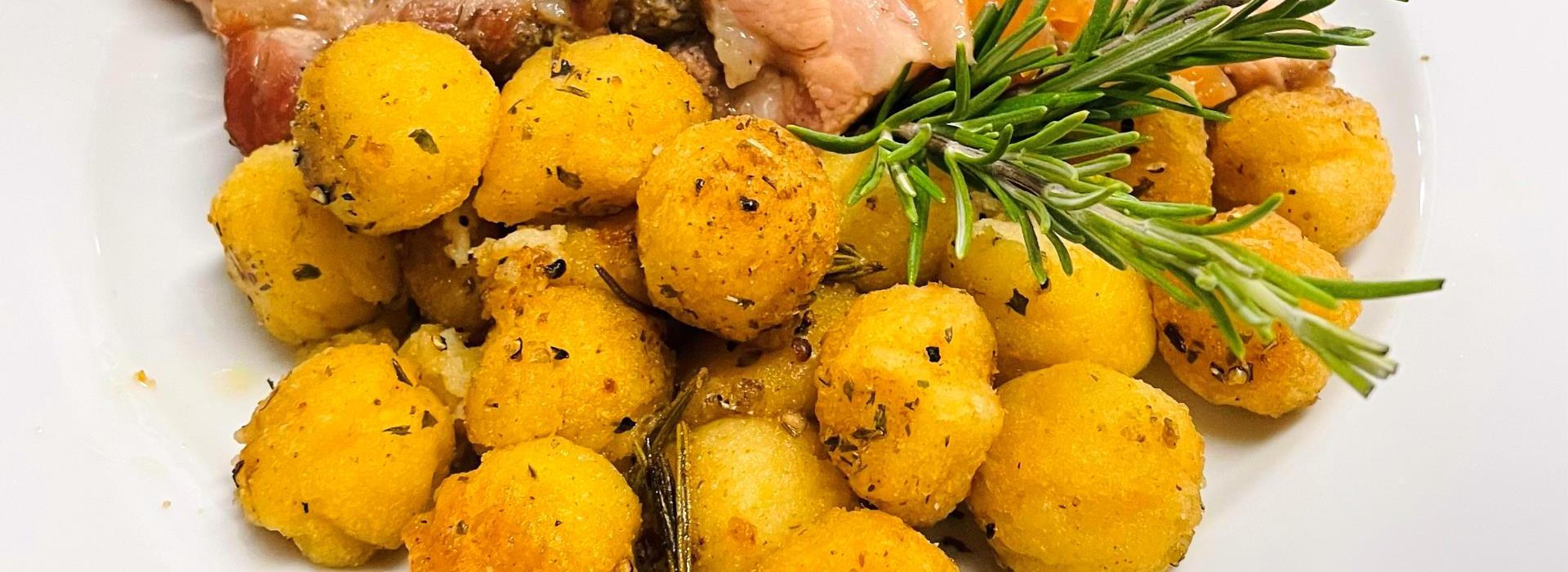 Piatto appetitoso con carne succulenta e croccanti gnocchi dorati, guarnito con rosmarino.