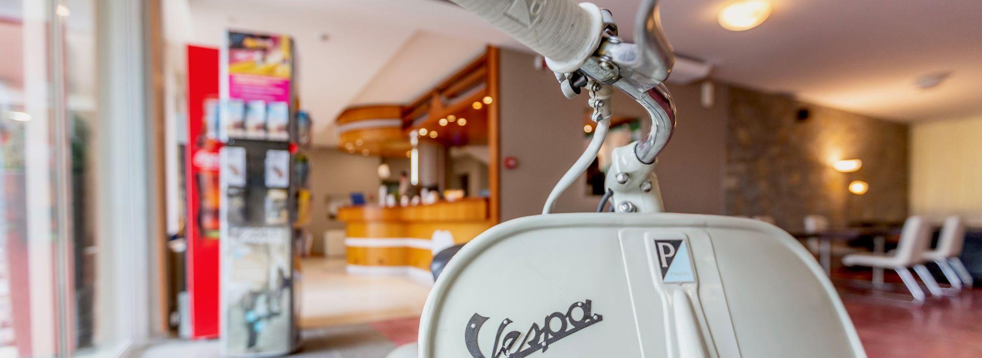 Una Vespa vintage in una hall moderna, evoca nostalgia e stile senza tempo.